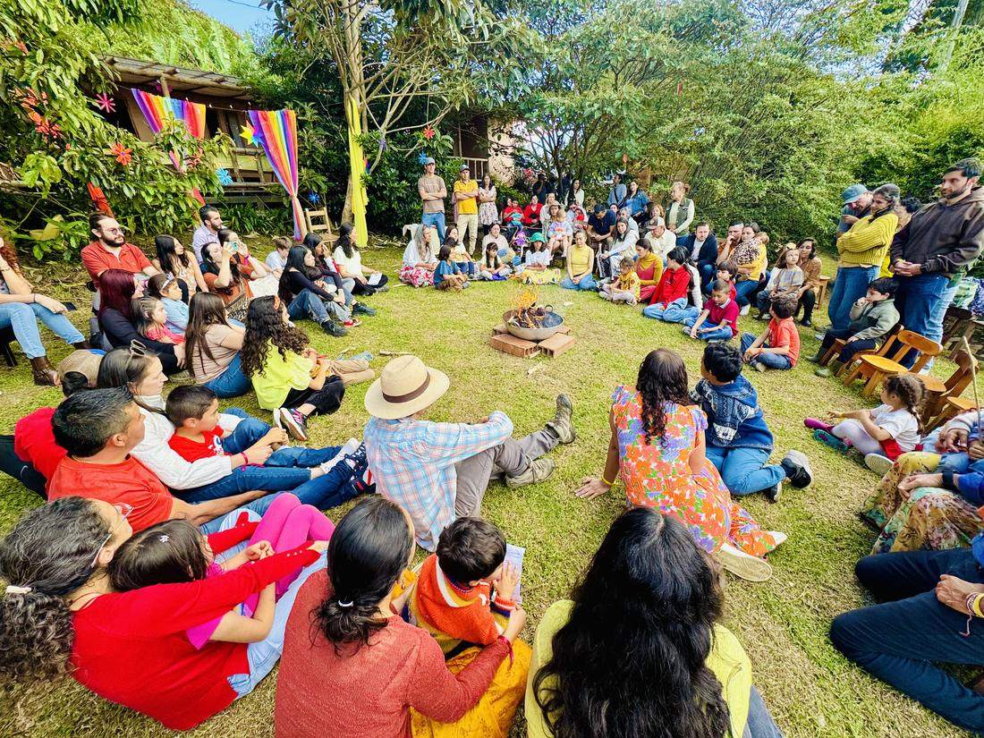 Familias reunidas en círculo alrededor del fuego durante un encuentro de Familias de Colores en Antioquia
